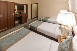 Una habitación de hotel con dos camas y una lámpara. en Snood Al Azizya, en La Meca