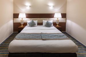 Un dormitorio con una cama grande con dos lámparas. en Snood Al Azizya, en La Meca