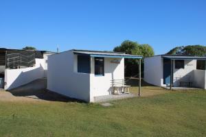 ein weißes Haus mit einer Veranda und einem Grasfeld in der Unterkunft VIssershuisies at Grootvlei Guest Farm 