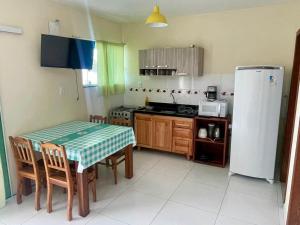 a small kitchen with a table and a refrigerator at Residencial Esmeralda-Vista ao Mar in Palhoça
