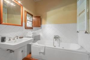 a white bathroom with a tub and a sink and a bath tubermott at Casa Dell'Ambasciatore in Vivo dʼOrcia +26 photos