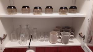 a shelf with glass vases and mugs on it at Apartmani Bogatić 3 in Bogatić
