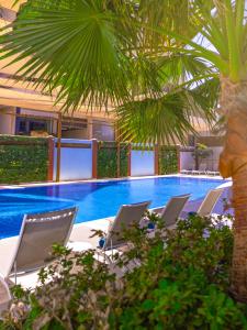 a pool with a bunch of chairs and a palm tree at Somerset Downtown Al Khobar in Al Khobar