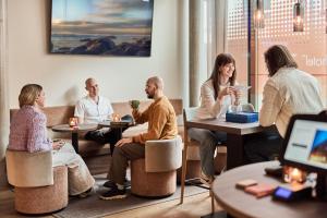a group of people sitting around tables in a room at Smarthotel Tromsø in Tromsø