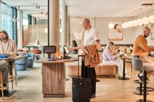 a man standing with a suitcase in a lobby at Smarthotel Tromsø in Tromsø