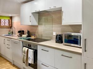a kitchen with white cabinets and a microwave at The Yeomans Cottage, Eastbridge Hospital in Canterbury