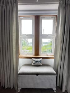einen Fensterplatz in einem Zimmer mit zwei Fenstern in der Unterkunft Dunmore Cottage in Whitehouse
