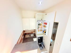 Elle comprend une petite cuisine avec des placards blancs et un réfrigérateur ouvert. dans l'établissement Independent Studio dans maison, à Avignon