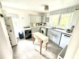 eine Küche mit weißen Schränken und einem Tisch darin in der Unterkunft Dunmore Cottage in Whitehouse