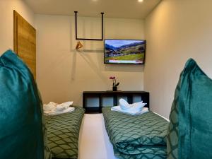 Habitación con 2 camas verdes y TV. en Haus Schernthaner, en Saalbach Hinterglemm