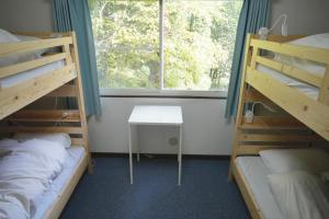 Habitación con 2 literas, mesa y ventana en Dear Hostel Hakuba, en Hakuba