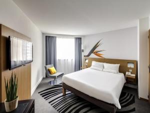 a hotel room with a large white bed and a chair at Novotel Paris Centre Gare Montparnasse in Paris +118 photos
