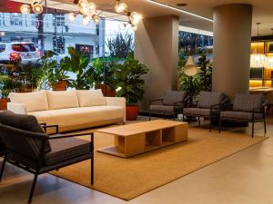 un hall d'entrée avec un canapé, une table et des chaises dans l'établissement Ibis Florianopolis, à Florianópolis