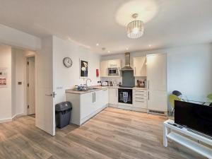 a large kitchen with white cabinets and a table at The Post House One by Fortuna Property in Gloucester