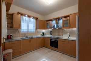 uma cozinha com armários de madeira, um lavatório e um fogão em Villa Pantelis with private pool em Agia Triada