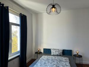 a bedroom with a bed and a window and a chandelier at Petit Chatelet Rooms in Saarbrücken