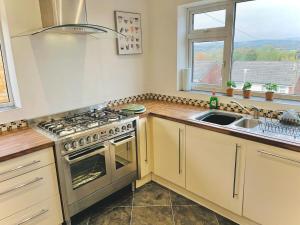 a kitchen with a stove and a sink and a window at Lovely 4-Bed home sleeps 8 Nr Bolton Stadium & M61 in Blackrod