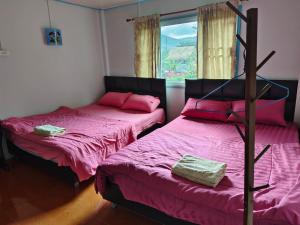 - 2 lits dans une chambre avec des draps roses et une fenêtre dans l'établissement อินทนนท์ บ้านพักเล่าจู Inthanon Laoju House, à Ban Na Yang