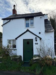 a white house with a green door at Rosebank Cottage in Boscastle