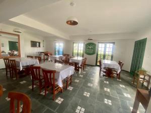 ein Esszimmer mit Tischen, Stühlen und Fenstern in der Unterkunft Pousada in Bombinhas