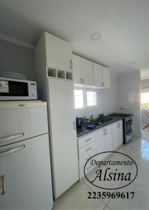 eine weiße Küche mit einem Kühlschrank und einer Mikrowelle in der Unterkunft Alsina Departmento in Necochea