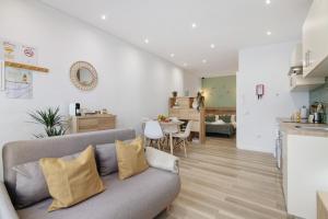 a living room with a couch and a kitchen at Central Studio – Flor De Sol in Tavira