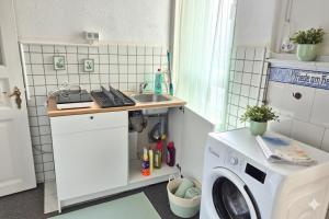 eine kleine Küche mit einer Waschmaschine und einem Waschbecken in der Unterkunft L21-Apartment Flensburg, 3 Zimmer, 7 Betten, Standardisierte Ausstattung, ideal für Reisende, Pendler, Familien in Flensburg