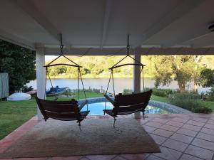 two chairs hanging from a pavilion with a pool at Whispering Waters Malgas in Malgas
