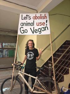 斋浦尔The Pink Nest - Backpackers Abode的一个男人站在一辆举着牌子的自行车旁