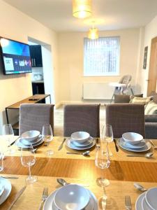 une table en bois avec des assiettes et des verres à vin dessus dans l'établissement Ideal 4-bed home sleeps 7 - Nr Trafford Ctr & M60, à Irlam