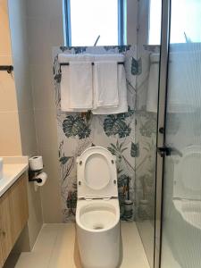 a bathroom with a toilet with a shower and towels at Artesano one bedroom cozy and comfortable in Syokimau +3 photos