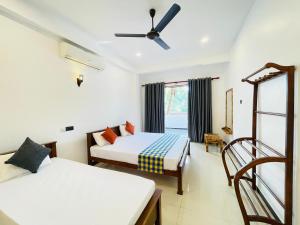 a bedroom with two beds and a ceiling fan at Sanu Surfing Villa in Weligama