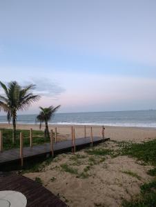 a person standing on a boardwalk on the beach at Vila Mar Lofts in Barra Velha +8 photos