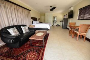 a living room with a black leather couch and a bed at Driftwood on 10 in Durban