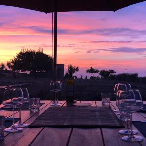 特雷斯努拉吉斯Anima Sarda Bed & Wine的一张摆放着酒杯的桌子和一把遮阳伞，夕阳西下。