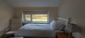a bedroom with a white bed and a window at Crillaun Cottage in Foxford