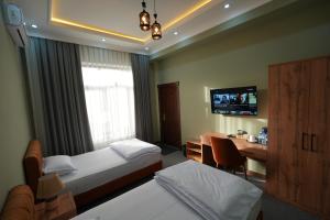 une chambre d'hôtel avec deux lits, un bureau et une télévision dans l'établissement Amin Guest House, à Samarcande