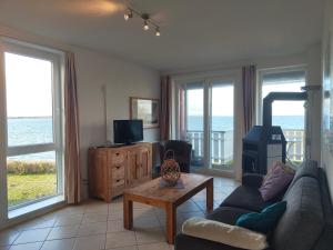 ein Wohnzimmer mit einem Sofa, einem TV und Fenstern in der Unterkunft Mitteldeck 503 in Rechlin