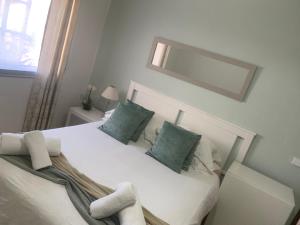 a bedroom with a white bed with green pillows and a mirror at Casa do Omega do Foz in Foz do Arelho