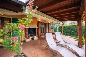 eine Terrasse mit weißen Stühlen und einem Kamin in der Unterkunft CASA FIORE Lago e Vigneti in Calmasino + 2 Fotos