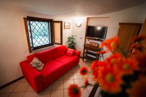 ein Wohnzimmer mit einem roten Sofa und einem Fenster in der Unterkunft CASA FIORE Lago e Vigneti in Calmasino