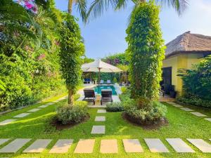 a garden with a swimming pool and two trees at Arjuna Villa 3 Bedroom Villa Seminyak in Seminyak