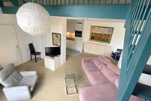 - un salon avec un canapé rose et une télévision dans l'établissement Hello Zeeland - Noordstraat 13-01, à Domburg
