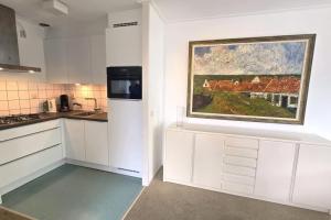 une cuisine avec des placards blancs et un tableau mural. dans l'établissement Hello Zeeland - Noordstraat 13-01, à Domburg