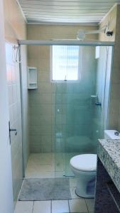 a bathroom with a glass shower with a toilet at com churrasqueira em Canasvieiras in Florianópolis