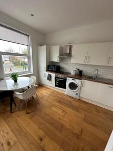 eine Küche mit weißen Schränken und einem Tisch und einem Fenster in der Unterkunft Cozy 1 Bed City Escape in Epsom + 2 Fotos