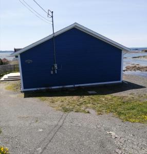 un bâtiment bleu avec une porte sur son côté dans l'établissement Oceanview Cottage, à North Twillingate Island
