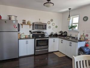 Eine Küche mit weißen Schränken und Edelstahlgeräten in der Unterkunft Oceanview Cottage in Twillingate + 11 Fotos