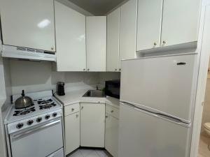Una cocina con gabinetes blancos y un refrigerador blanco. en Parkline Suites Upper West Side, en Nueva York