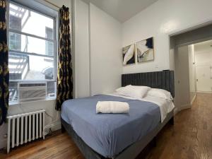 Un dormitorio con una cama con una manta azul y una ventana. en Parkline Suites Upper West Side, en Nueva York